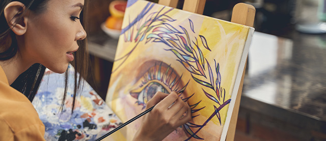 mulher praticando arteterapia enquanto pinta um olho em um quadro