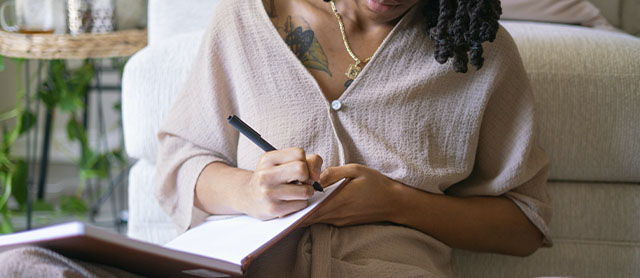 mulher sentada no chão escrevendo em seu diário