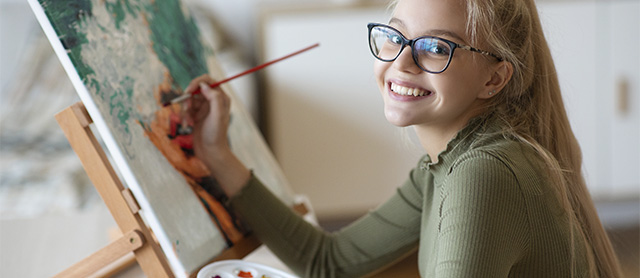 garota pintando uma tela e sorrindo