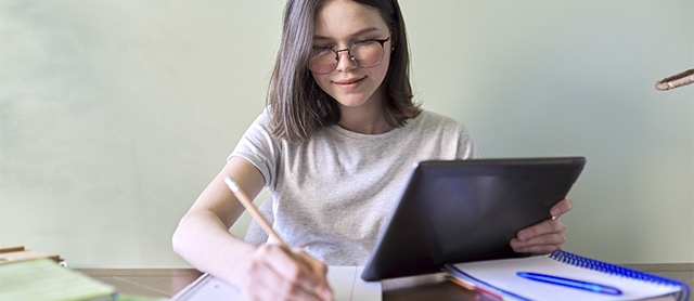 garota estudando com seu material escolar organizado sobre a escrivaninha