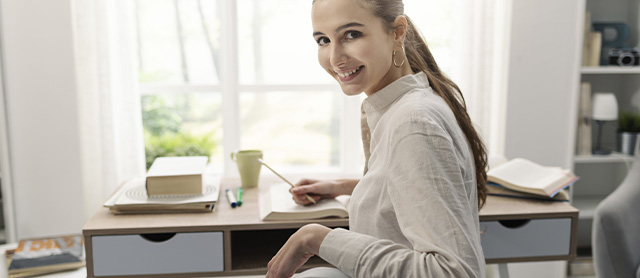 garota sorrindo com a mão apoiada em sua escrivaninha