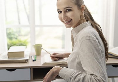 garota sorrindo com a mão apoiada em sua escrivaninha